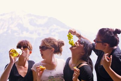 Friends drinking water in swimming pool against sky