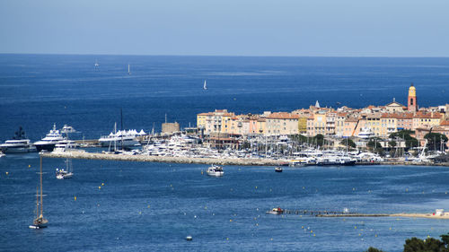 Sailboats in sea by buildings against sky