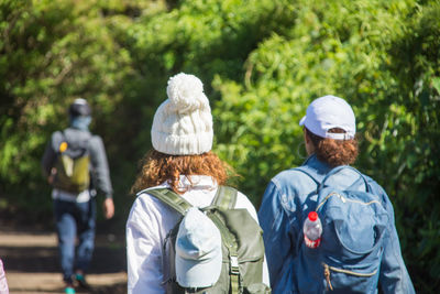 Rear view of friends walking by trees