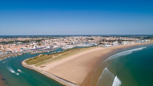 Aerial view of city by sea against clear blue sky