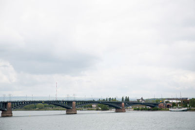 Bridge over river against cloudy sky