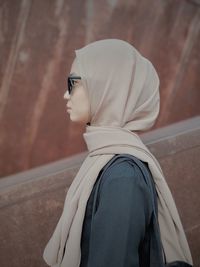 Portrait of young woman standing against wall