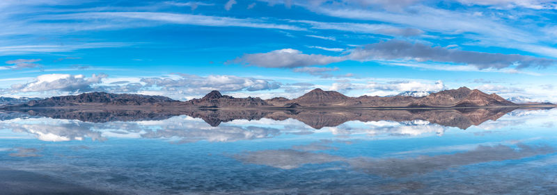 Scenic view of lake by snowcapped mountains against sky