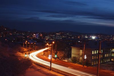 High angle view of light trails on street by buildings at night