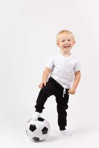Cute boy playing soccer ball against white background
