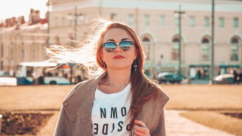 Portrait of young woman wearing sunglasses standing outdoors