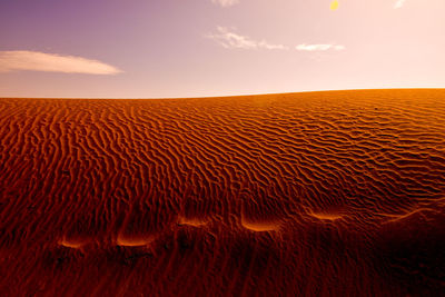 Scenic view of sand dune against sky during sunset