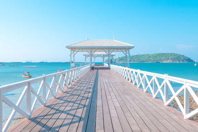 Pier over sea against clear blue sky