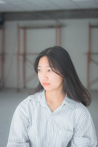 Thoughtful young woman against wall