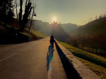 Rear view of man walking on road against sky