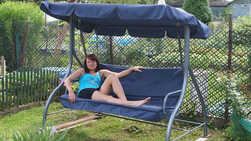 Young woman relaxing on swing in yard