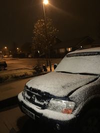 Illuminated car on snow against sky at night