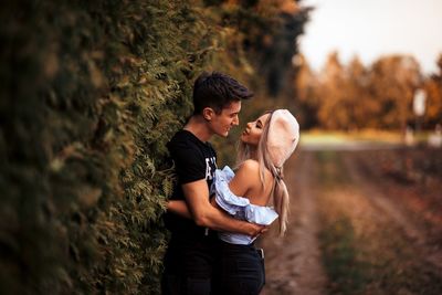 Young couple standing against plants