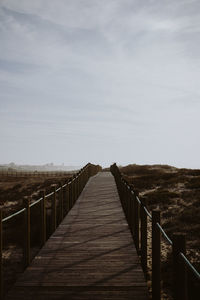 Boardwalk amidst landscape against sky