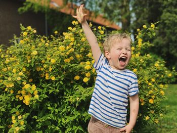 Happy boy screaming while standing against plants