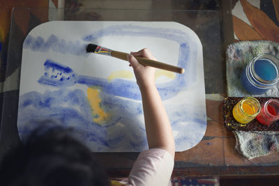 Low angle view of hand holding painting on table