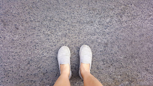 Low section of woman standing on asphalt