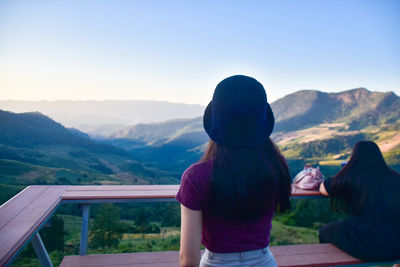 Rear view of woman looking at mountains against clear sky