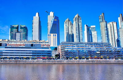 Modern buildings in city against clear blue sky