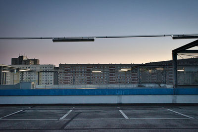 Empty road against buildings in city at sunset