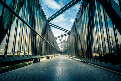 Empty footbridge against sky in city