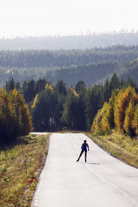 Full length of man on road amidst trees during autumn