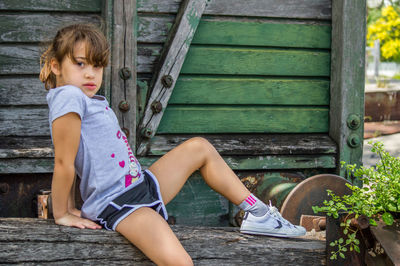 Portrait of young woman sitting on wood