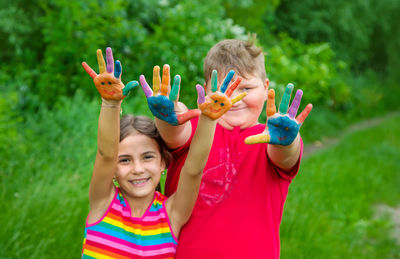 Smiling girl and boy showing colored palm of hands