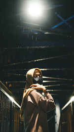 Low angle view of woman with umbrella at night