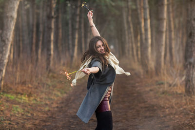 Full length of young woman standing in forest