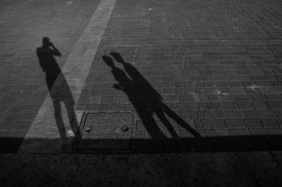 Shadow of people walking on footpath