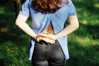 Midsection of woman holding umbrella while standing on field