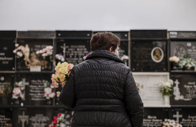 Old lady with mask mourning her family in cemetery. almeria, spain