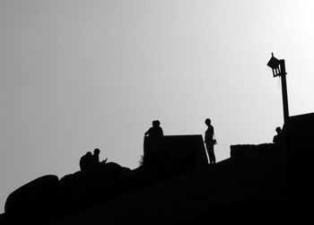 Low angle view of silhouette men against clear sky