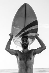 Portrait of shirtless man in sea against sky
