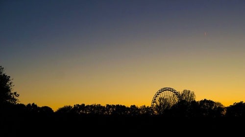 Silhouette ferris wheel against clear sky during sunset