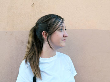 Portrait of young woman against wall