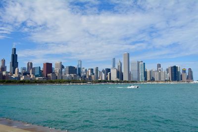 Sea by modern buildings against sky in city