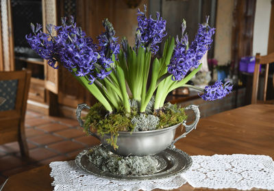 Large pewter vase with purple hyacinths on a table in the hall in a rustic style