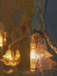 Close-up of illuminated lighting equipment hanging on glass