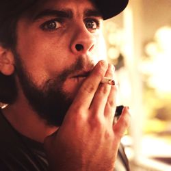 Close-up portrait of young man smoking cigarette