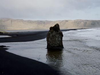 Rock formation on beach against sky