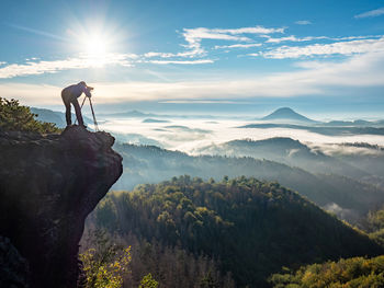 Photographer framing scene in viewfinder. man is using camera on tripod for taking pictures of land