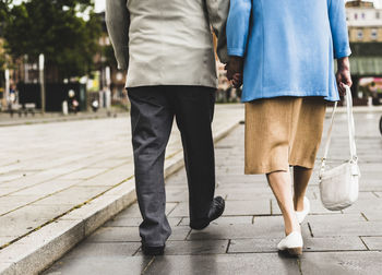 Back view of walking senior couple holding hands