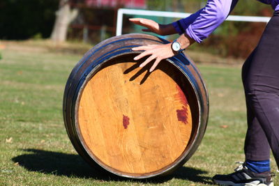 Low section of man pushing wine cask on grassy field