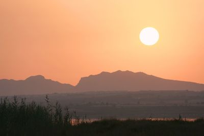 Grass with silhouetted mountains at dusk