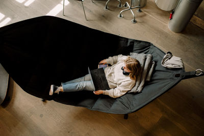 High angle view of businesswoman with laptop sitting on hammock in office