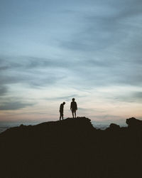 Silhouette people standing on land against sky during sunset