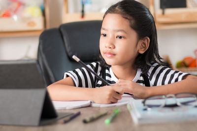 Girl writing on book at table