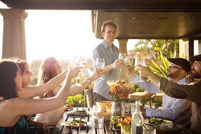 Friends toasting wineglasses while enjoying at table at porch